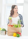 Beautiful pregnant woman in the kitchen with shopping bag and apple Royalty Free Stock Photo