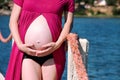 Beautiful pregnant woman and lady is hugging and holding her pregnant belly, standing in natural environment. Waiting for baby. Royalty Free Stock Photo