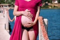 Beautiful pregnant woman and lady is hugging and holding her pregnant belly, standing in natural environment. Waiting for baby. Royalty Free Stock Photo