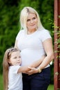 Beautiful pregnant woman and little daughter. Cute little girl  hugging her pregnant  mother  in summer nature Royalty Free Stock Photo