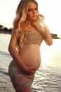 Beautiful pregnant woman with long blond hair posing on sunset beach Royalty Free Stock Photo