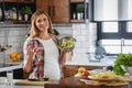 Beautiful pregnant woman preparing healthy meal with lots of vegetables at home Royalty Free Stock Photo