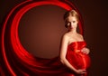 Beautiful pregnant woman in red silk dress billowing Royalty Free Stock Photo