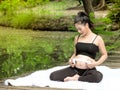 Beautiful pregnant women sit in the park, let the children in the belly listen to music from headphones Royalty Free Stock Photo