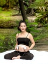 Beautiful pregnant women sit in the park, let the children in the belly listen to music from headphones Royalty Free Stock Photo