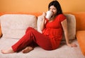 Beautiful pregnant woman sitting on the couch Royalty Free Stock Photo