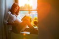 Beautiful pregnant woman, sitting on window shield, reading a bo Royalty Free Stock Photo