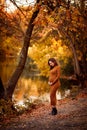 Pregnant in slinky dress in autumn Park by river. Royalty Free Stock Photo