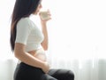 A beautiful pregnant woman standing, holding her stomach and drinking soy milk Royalty Free Stock Photo