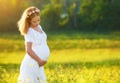 Beautiful pregnant woman in summer nature meadow with yellow flo