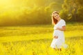 Beautiful pregnant woman in summer nature meadow with yellow flo Royalty Free Stock Photo