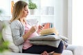 Beautiful pregnant woman texting with her smartphone and eating yogurt on the sofa at home. Royalty Free Stock Photo