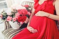 Beautiful pregnant woman touching her belly with hands in the living room Royalty Free Stock Photo