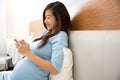 Beautiful pregnant woman using mobile phone in her bedroom Royalty Free Stock Photo