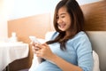 Beautiful pregnant woman using mobile phone in her bedroom Royalty Free Stock Photo