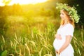 Beautiful pregnant woman in wreath relaxing in summer nature Royalty Free Stock Photo