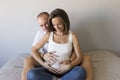 Beautiful pregnant woman and her handsome husband are hugging and smiling while spending time together. Love and couple lifestyle Royalty Free Stock Photo