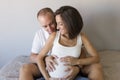 Beautiful pregnant woman and her handsome husband are hugging and smiling while spending time together. Love and couple lifestyle Royalty Free Stock Photo