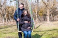 Beautiful pregnant woman and her handsome husband hugging the tummy on the swing Royalty Free Stock Photo