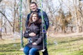 Beautiful pregnant woman and her handsome husband hugging the tummy on the swing Royalty Free Stock Photo