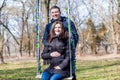 Beautiful pregnant woman and her handsome husband hugging the tummy on the swing Royalty Free Stock Photo