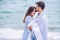 Beautiful pregnant woman and her respectable man leaning against each other and covered with a white striped plaid on