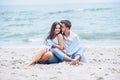 Beautiful pregnant woman and her respectable man leaning against each other and covered with a white striped plaid