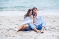 Beautiful pregnant woman and her respectable man leaning against each other and covered with a white striped plaid