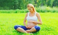 Beautiful pregnant young woman doing yoga on the grass in sunny summer park Royalty Free Stock Photo