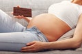 Beautiful pregnant young woman eating chocolate at home Royalty Free Stock Photo