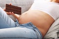 Beautiful pregnant young woman eating chocolate at home Royalty Free Stock Photo