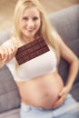 Beautiful pregnant young woman eating chocolate at home Royalty Free Stock Photo