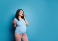 Beautiful pregnant young woman eating freah sweet strawberries out of bowl, blue background. Pregnancy. Healthy eating Royalty Free Stock Photo