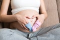 Beautiful pregnant young woman holding a pair of cute baby socks on her tummy, lying on sofa at home Royalty Free Stock Photo