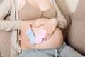 Beautiful pregnant young woman holding a pair of cute baby socks on her tummy, lying on sofa at home Royalty Free Stock Photo