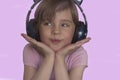 A beautiful preschool girl in wireless headphones smiles sweetly and listens to funny songs