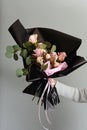 Beautiful present of pink tender blooming bouquet. Various fresh flowers and decorative plants in black paper. Gift idea for Valen