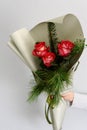 Beautiful present of red tender blooming bouquet. Various fresh flowers and pine branches in white paper. Gift idea for Valentines