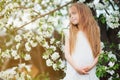 Beautiful preteen girl with long blond hair enjoy spring apple blooming. Royalty Free Stock Photo