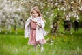 Beautiful preteen girl with long blond hair enjoy spring apple blooming. Little preschool girl runing  in garden tree flowers. Royalty Free Stock Photo