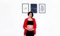 Beautiful and pretty pregnant woman standing with smiling and touching or holding her belly with white wall background Royalty Free Stock Photo