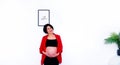 Beautiful and pretty pregnant woman standing with smiling and touching or holding her belly with white wall background and copy sp Royalty Free Stock Photo