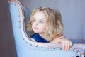 Beautiful pretty toddler girl sitting in arm-chair, looking away Royalty Free Stock Photo