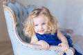 Beautiful pretty toddler girl sitting in arm-chair, smiling.