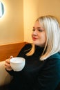 Beautiful, pretty woman, blonde girl in cozy coffee shop cafe. Romantic breakfast, lunch with cup, mug of coffee, tea Royalty Free Stock Photo