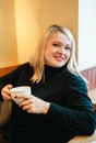 Beautiful, pretty woman, blonde girl in cozy coffee shop cafe. Romantic breakfast, lunch with cup, mug of coffee, tea Royalty Free Stock Photo