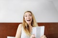 Young woman happy shocked with tablet looking at camera at white bed