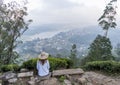 Beautiful pretty woman in the hat sitting at the top of the hill with view on the town Royalty Free Stock Photo