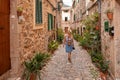 Beautiful pretty woman walking at old town pavement street with flowers and looking away. Travel concept Royalty Free Stock Photo