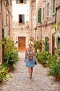 Beautiful pretty woman walking at old town pavement street with flowers and looking away. Travel concept Royalty Free Stock Photo